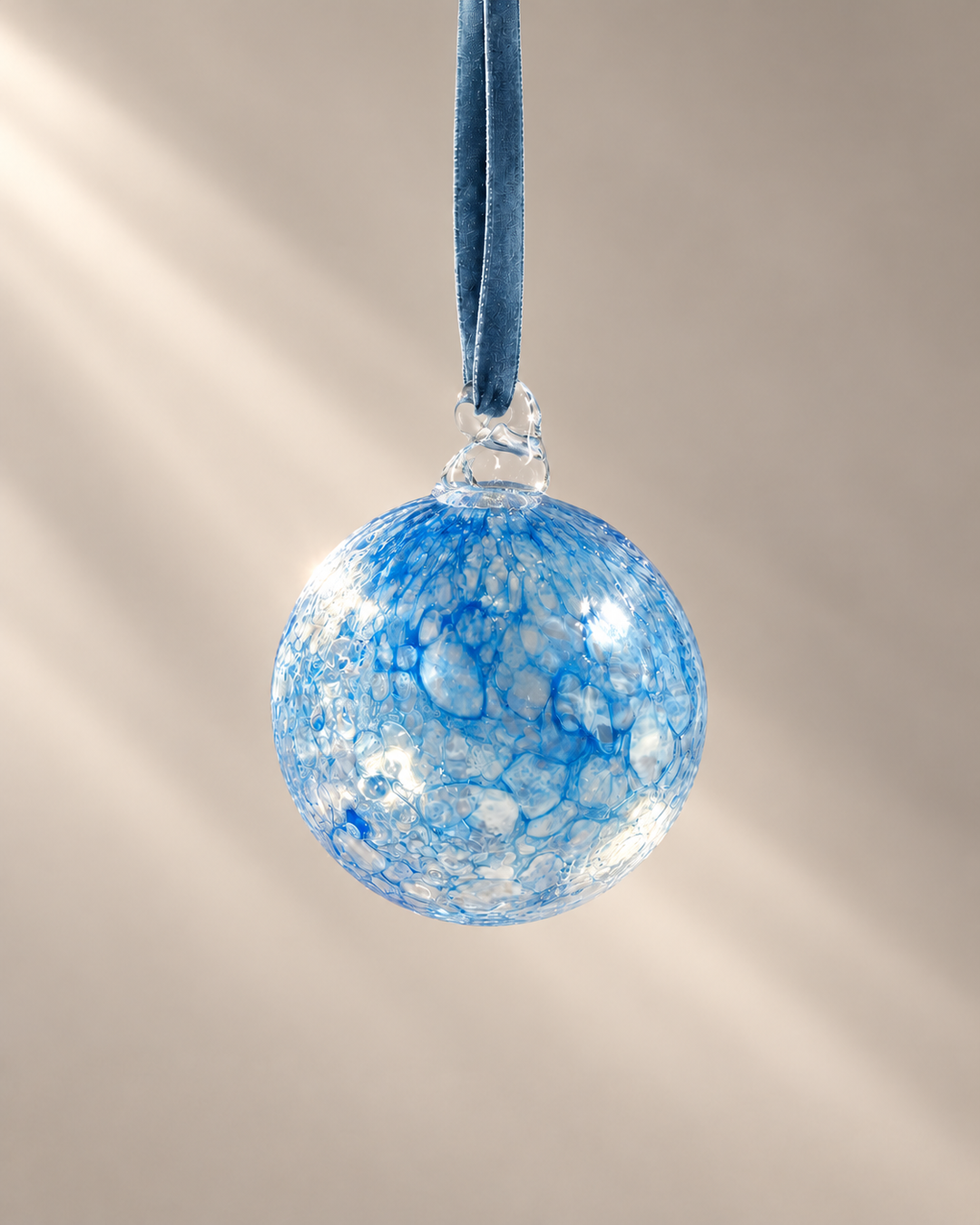 Blue Lagoon Glass Bauble hanging from a velvet ribbon
