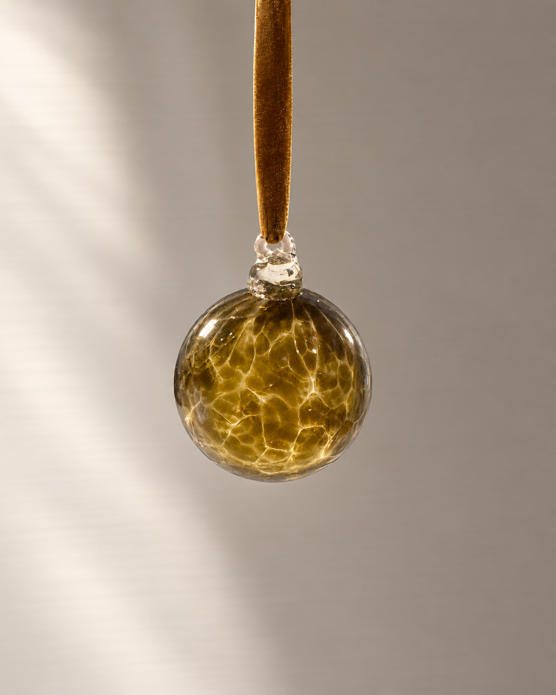 Miniature Olive Amber Glass Bauble hanging from a velvet ribbon