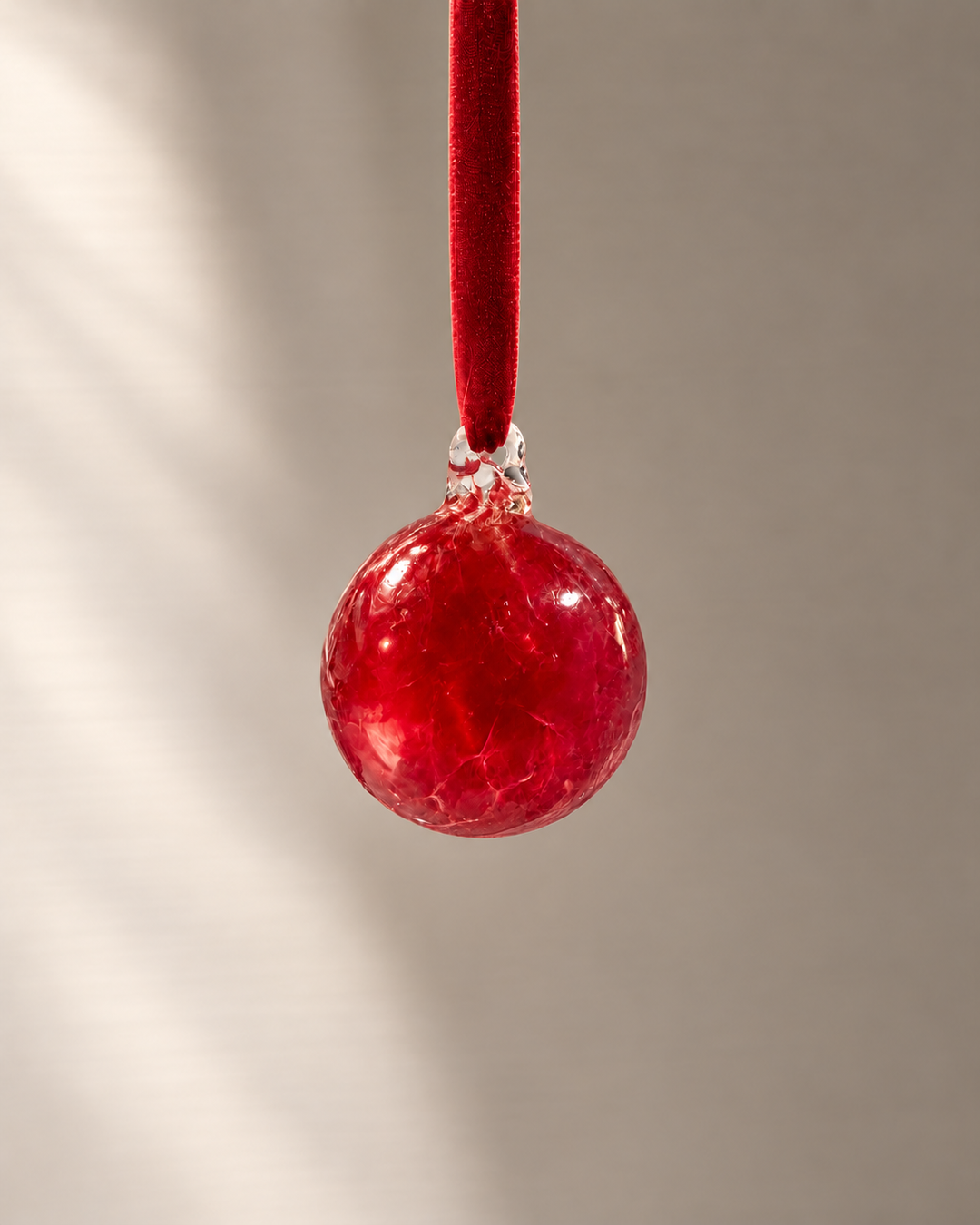 Miniature Ruby Red Glass Bauble hanging from a velvet ribbon