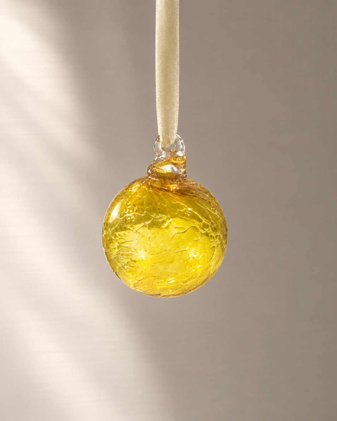 Miniature Yellow Glass Bauble hanging from a velvet ribbon