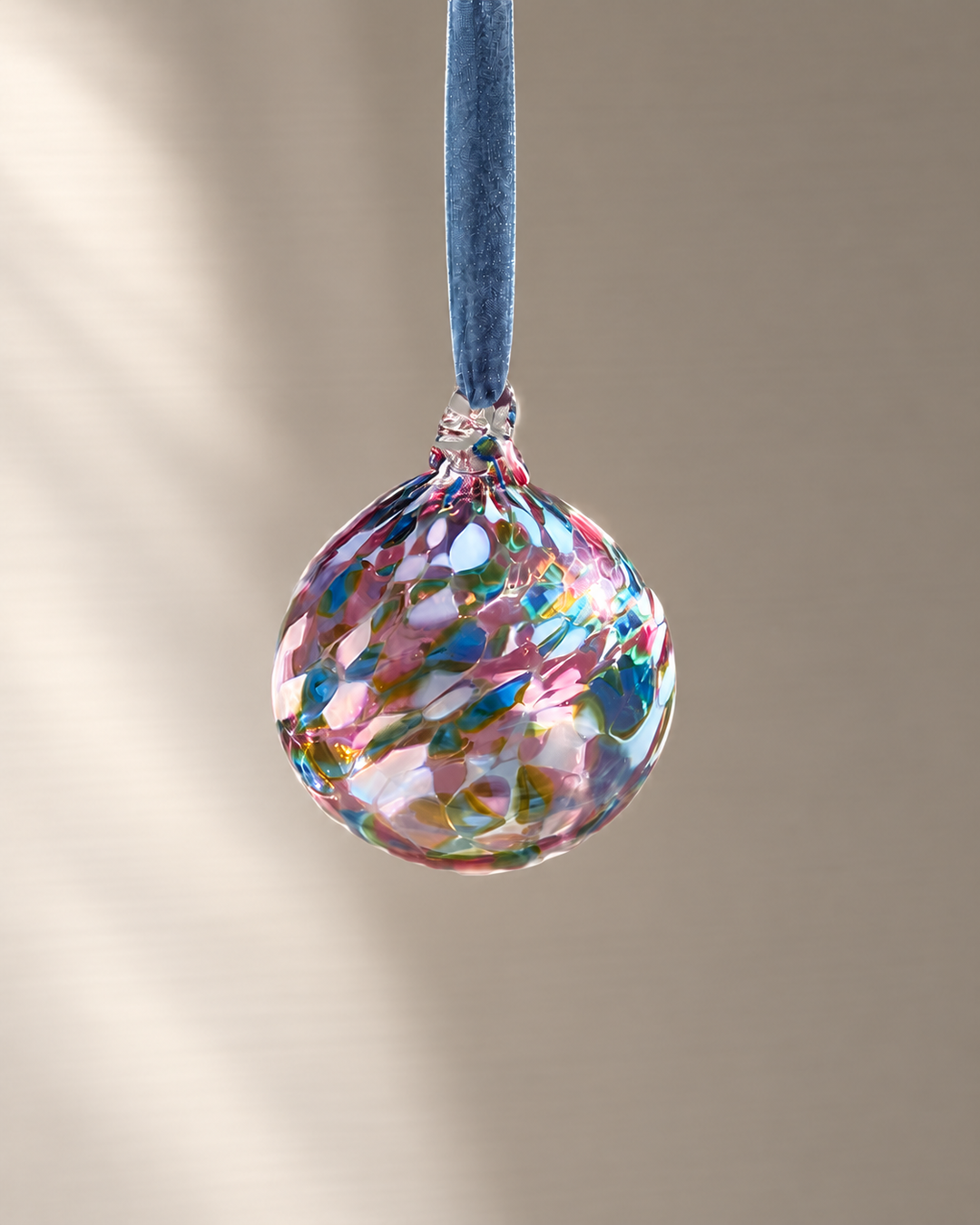 Peacock Glass Bauble hanging from a velvet ribbon