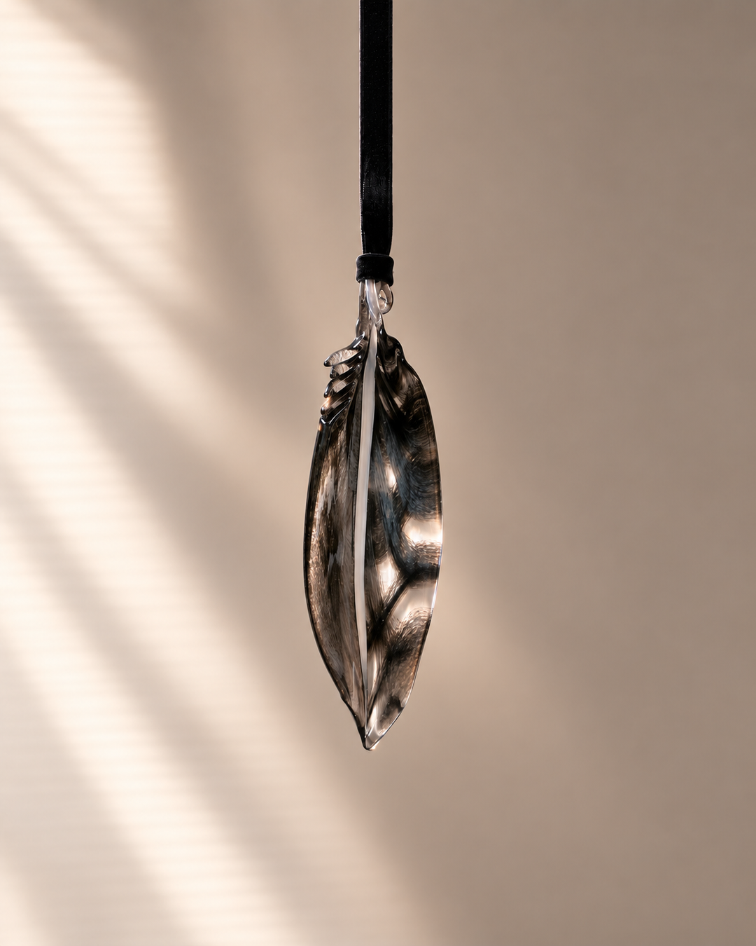 Smoke Black Glass Feather hanging on velvet ribbon