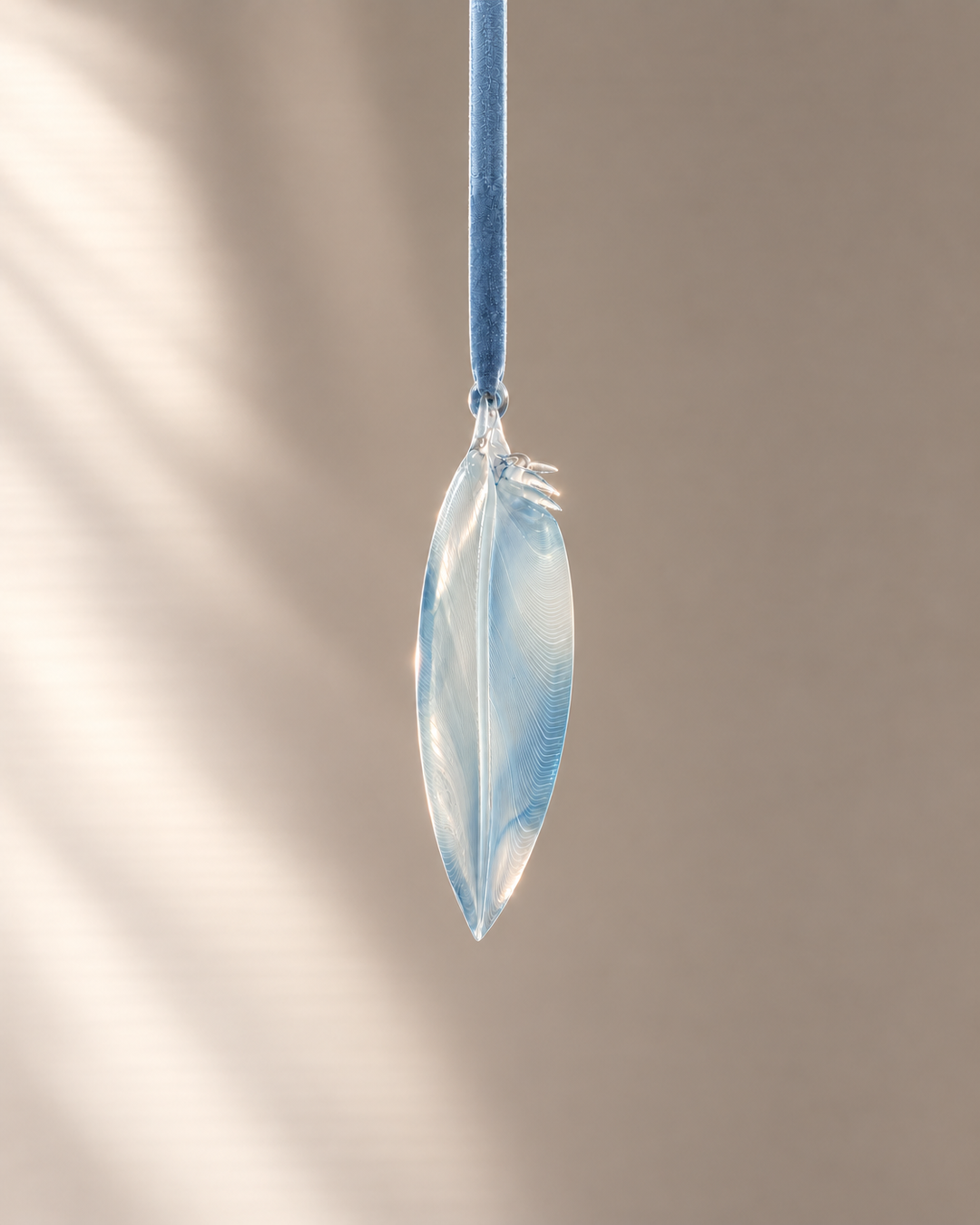 Pale Blue Caned Glass Feather hanging on velvet ribbon