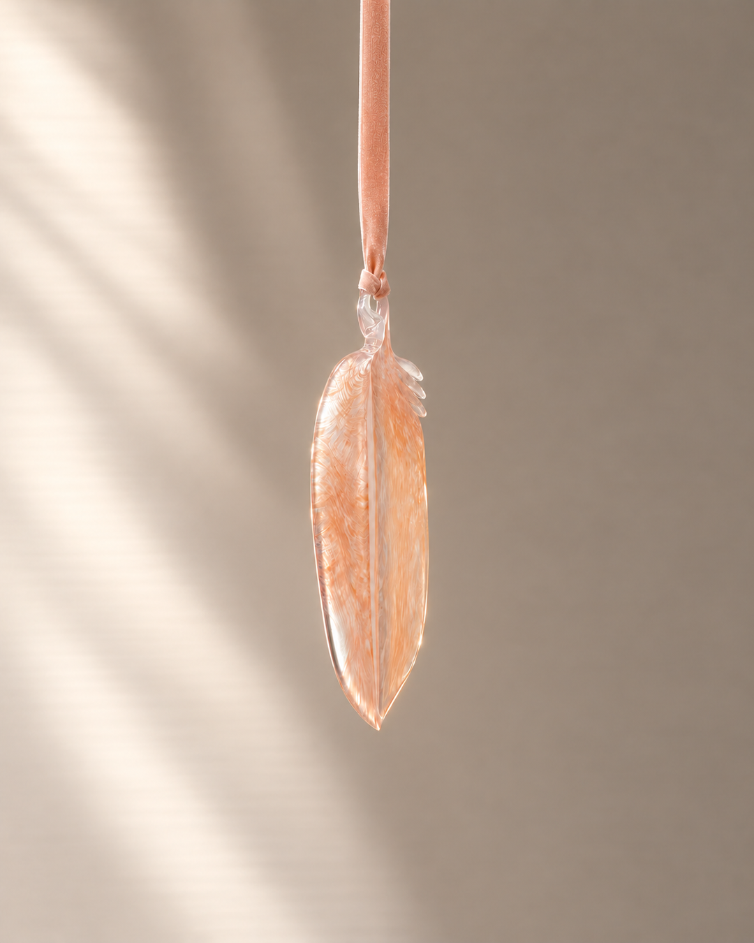 Peach Glass Feather hanging on velvet ribbon