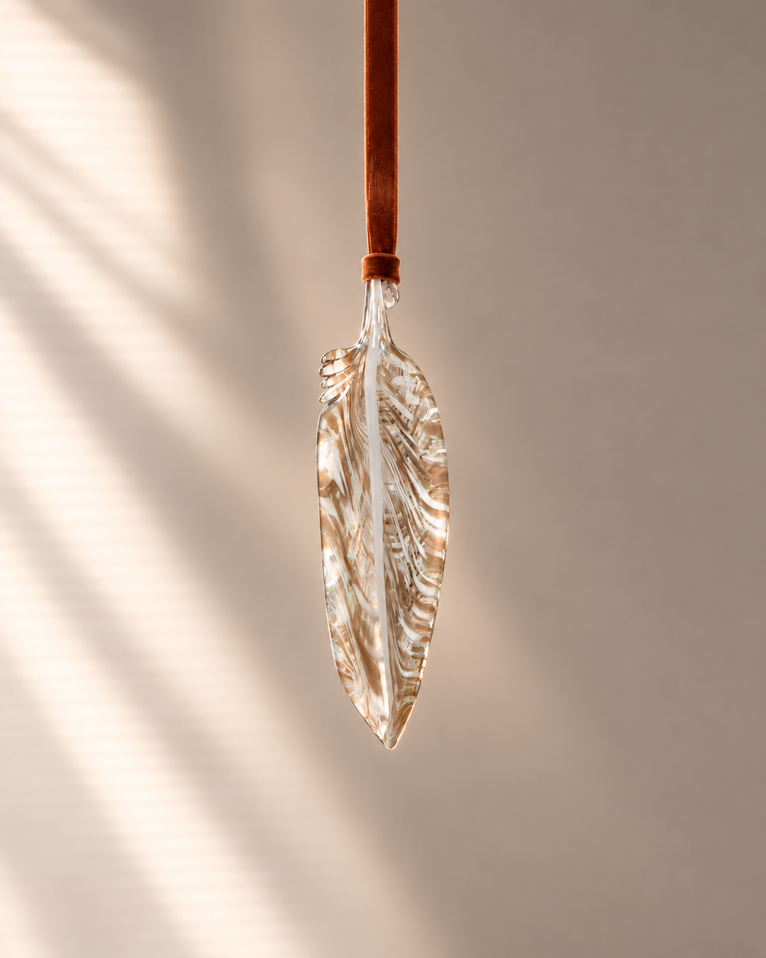 Tawny Glass Feather hanging on velvet ribbon
