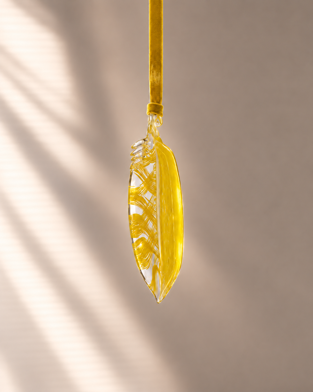 Yellow Glass Feather hanging on velvet ribbon