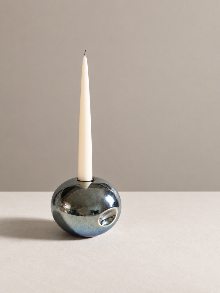 Dimpled metallic candlestick holder with cream taper, positioned left with spacious studio framing