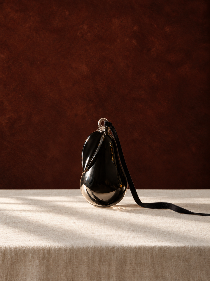 Smoke Hanging Glass Pear standing on ivory linen against a dark backdrop