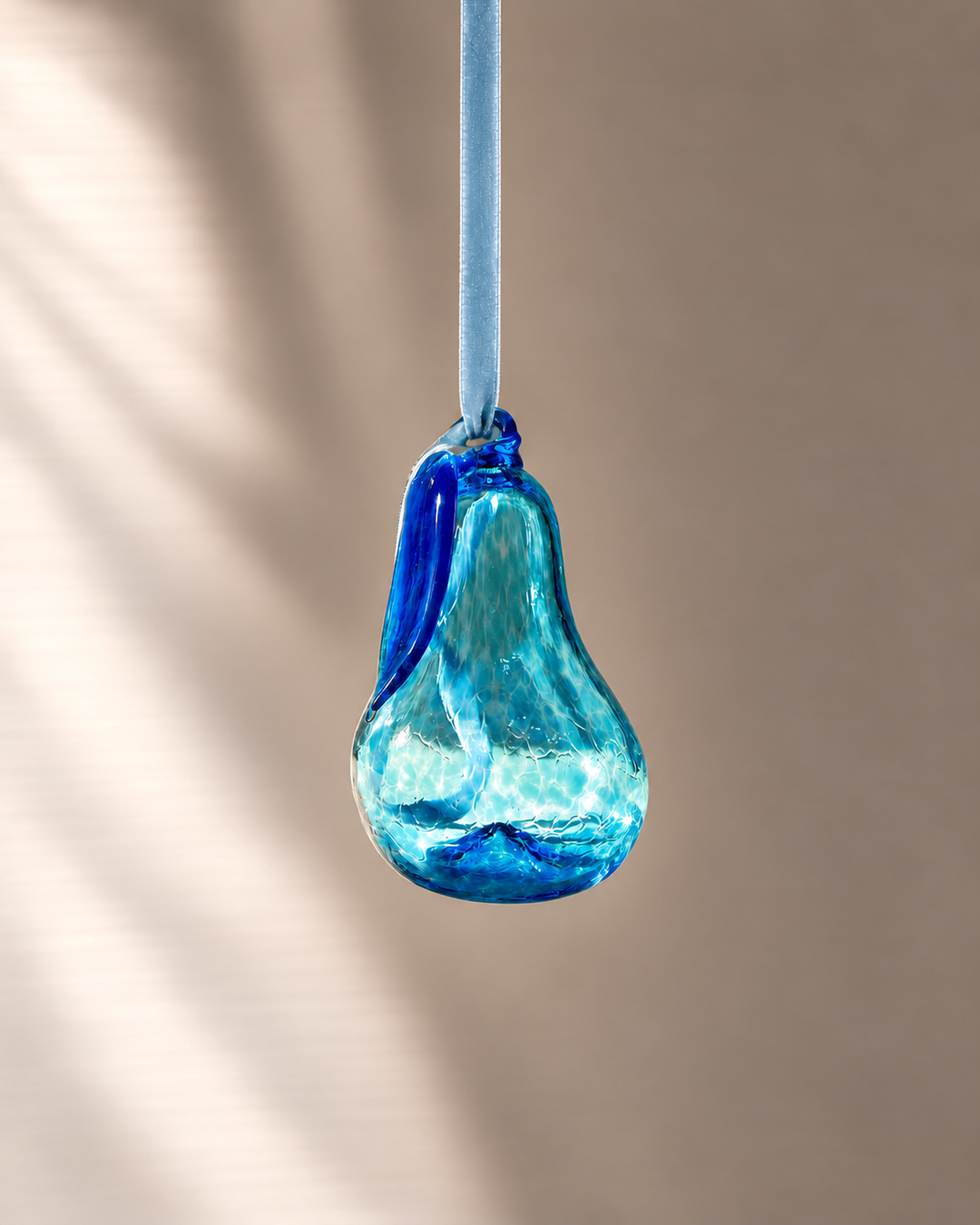 Turquoise hanging glass pear on pale blue velvet
